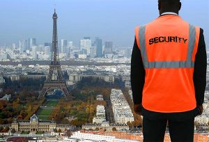 image d'un homme debout regardant la Tour Eiffel à Paris portant un gilet orange sécurité afin d'illustrer notre article sur la sécurité pour les jeux olympiques 2024 à Paris.