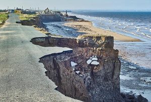 Image d'une route sur la côte qui est partiellement détruite du fait de l'érosion côtière
